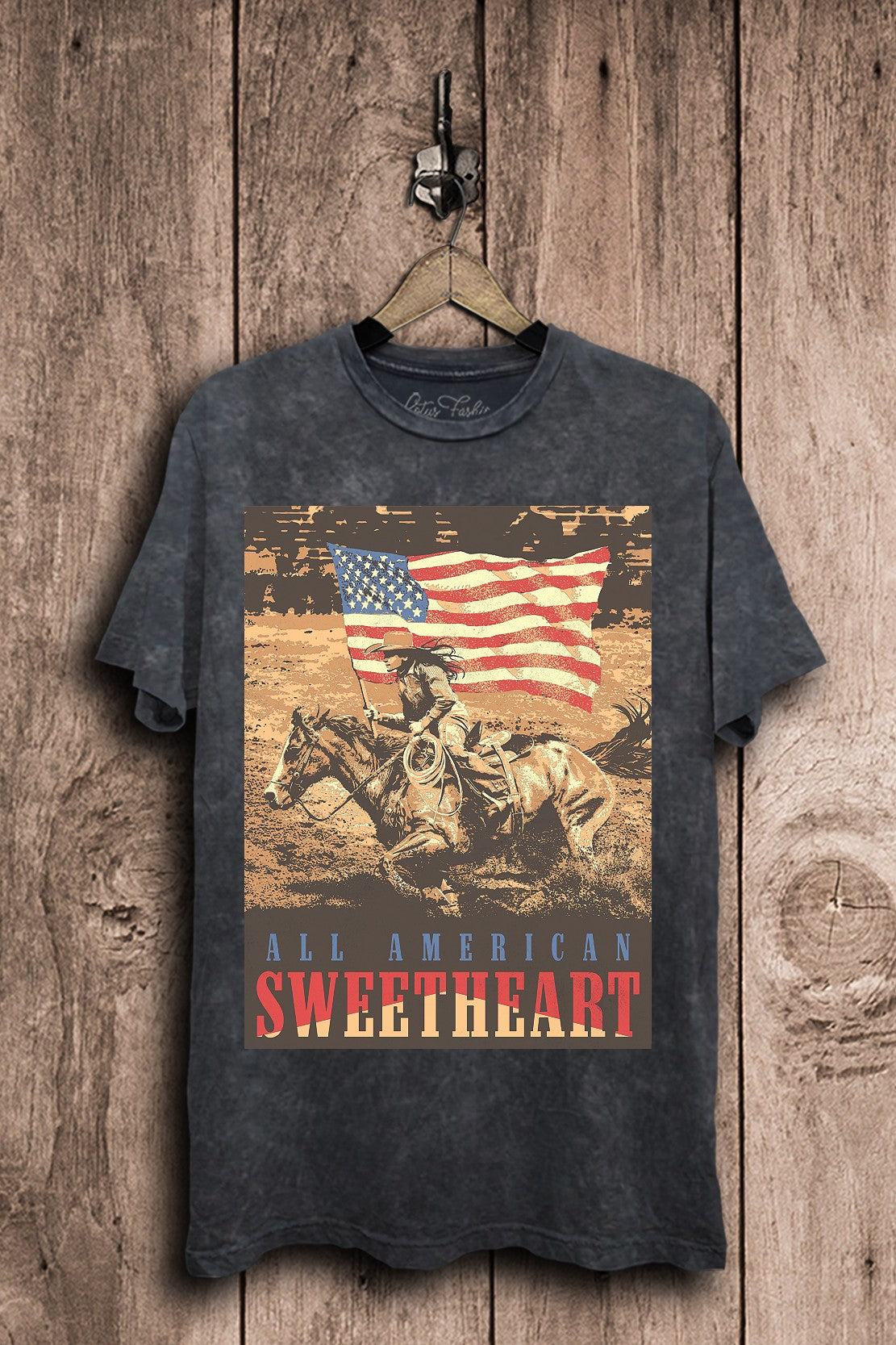 Vintage black mineral-wash boyfriend tee featuring a cowgirl riding on horseback beneath an American flag with All American Sweetheart lettering.