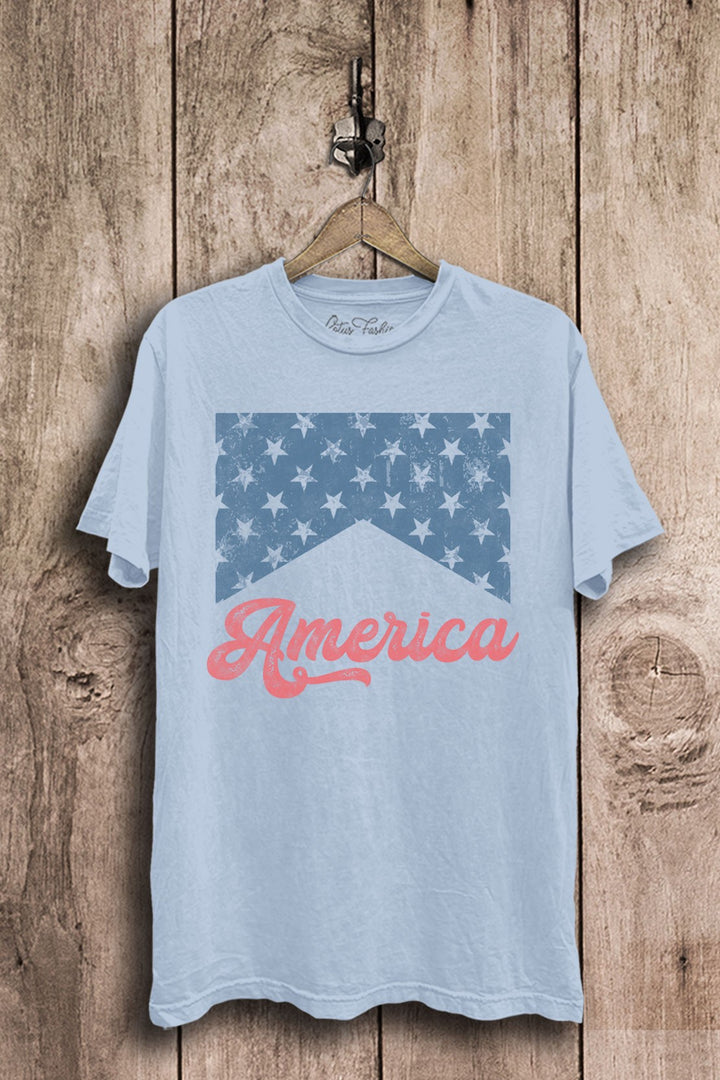 Light blue mineral-washed boyfriend tee featuring a distressed blue star-banner graphic and coral America script lettering.