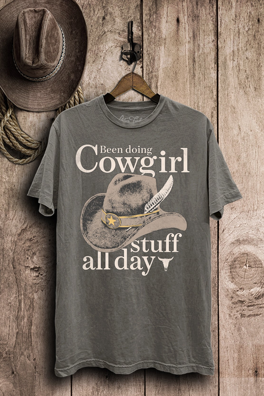 Stone-gray mineral-wash boyfriend tee with a vintage cowboy hat and Been Doing Cowgirl Stuff All Day lettering.