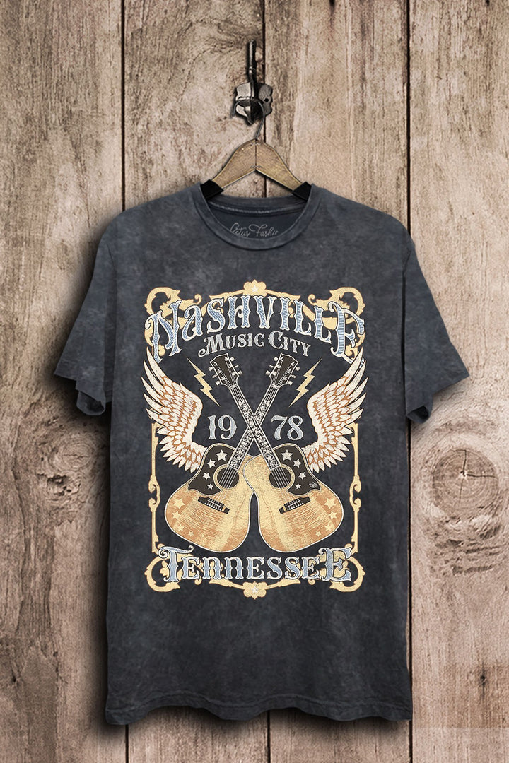 Vintage black mineral-washed plus-size boyfriend tee featuring ornate Nashville Music City lettering, crossed acoustic guitars, wings, stars, and lightning bolts.