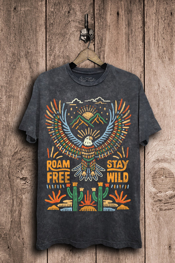 Vintage black mineral-washed boyfriend tee featuring a colorful soaring eagle, mountain peaks, rising suns, desert cacti, and Roam Free Stay Wild lettering.