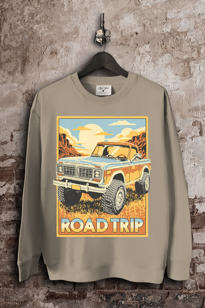 Mocha French terry crewneck sweatshirt featuring a vintage blue and orange off-road truck traveling through a sunlit canyon with Road Trip lettering.