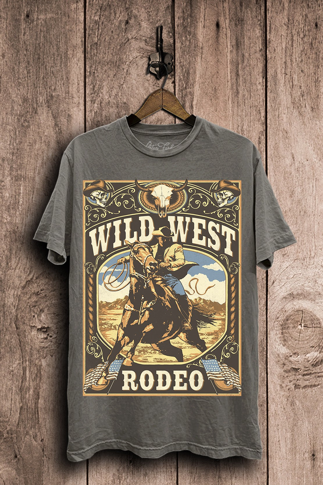 Stone-gray mineral-wash boyfriend tee featuring a vintage Wild West rodeo poster with a cowboy riding horseback, western skulls, and ornate details.