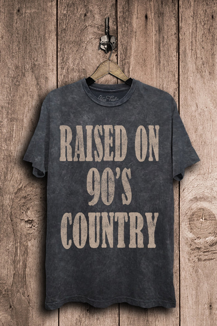 Vintage black mineral-washed boyfriend tee featuring oversized distressed tan lettering that reads Raised on 90s Country.