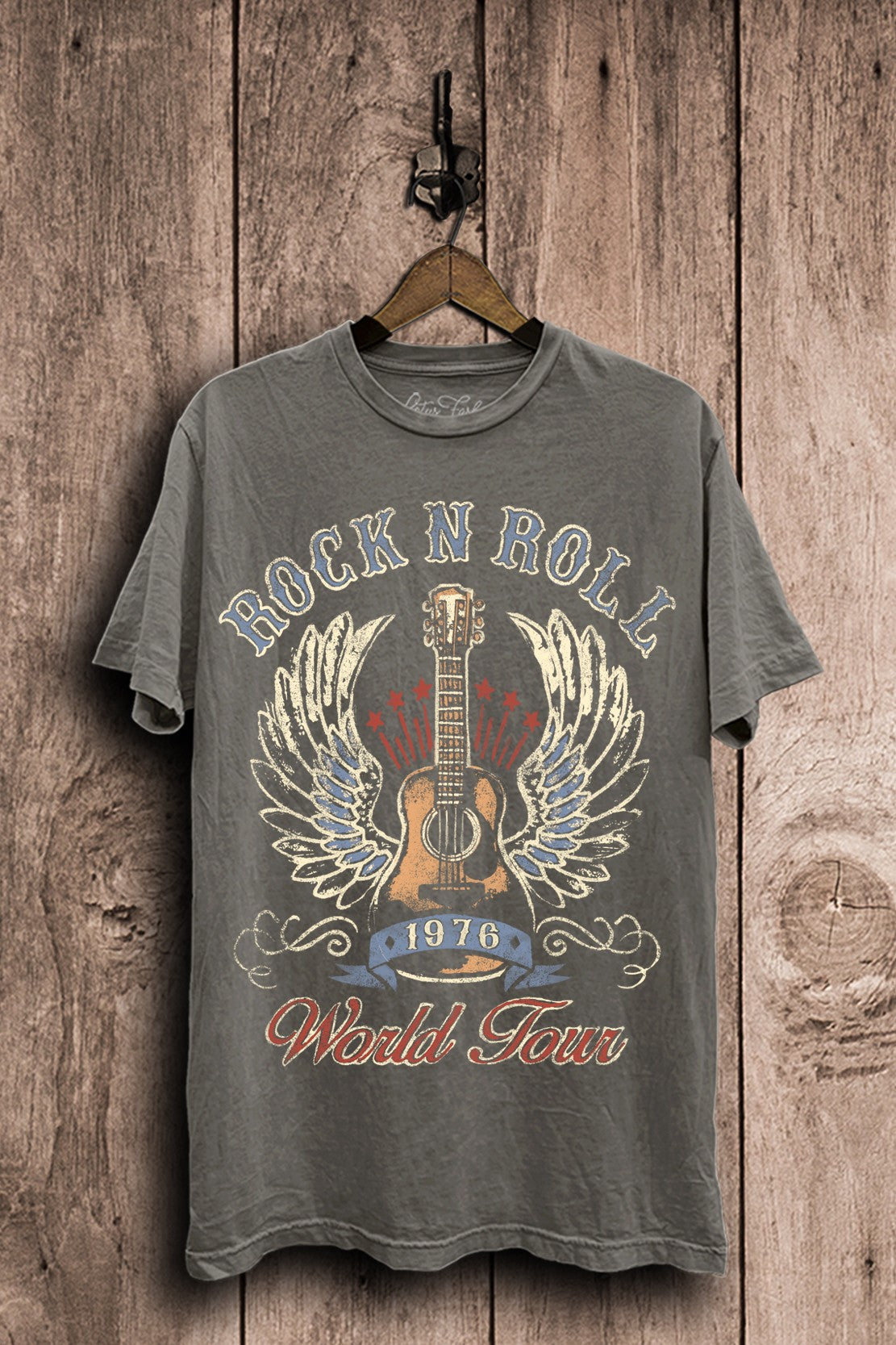 Stone gray mineral-washed plus-size boyfriend tee featuring a distressed acoustic guitar with wings, stars, 1976 banner, and Rock N Roll World Tour lettering.