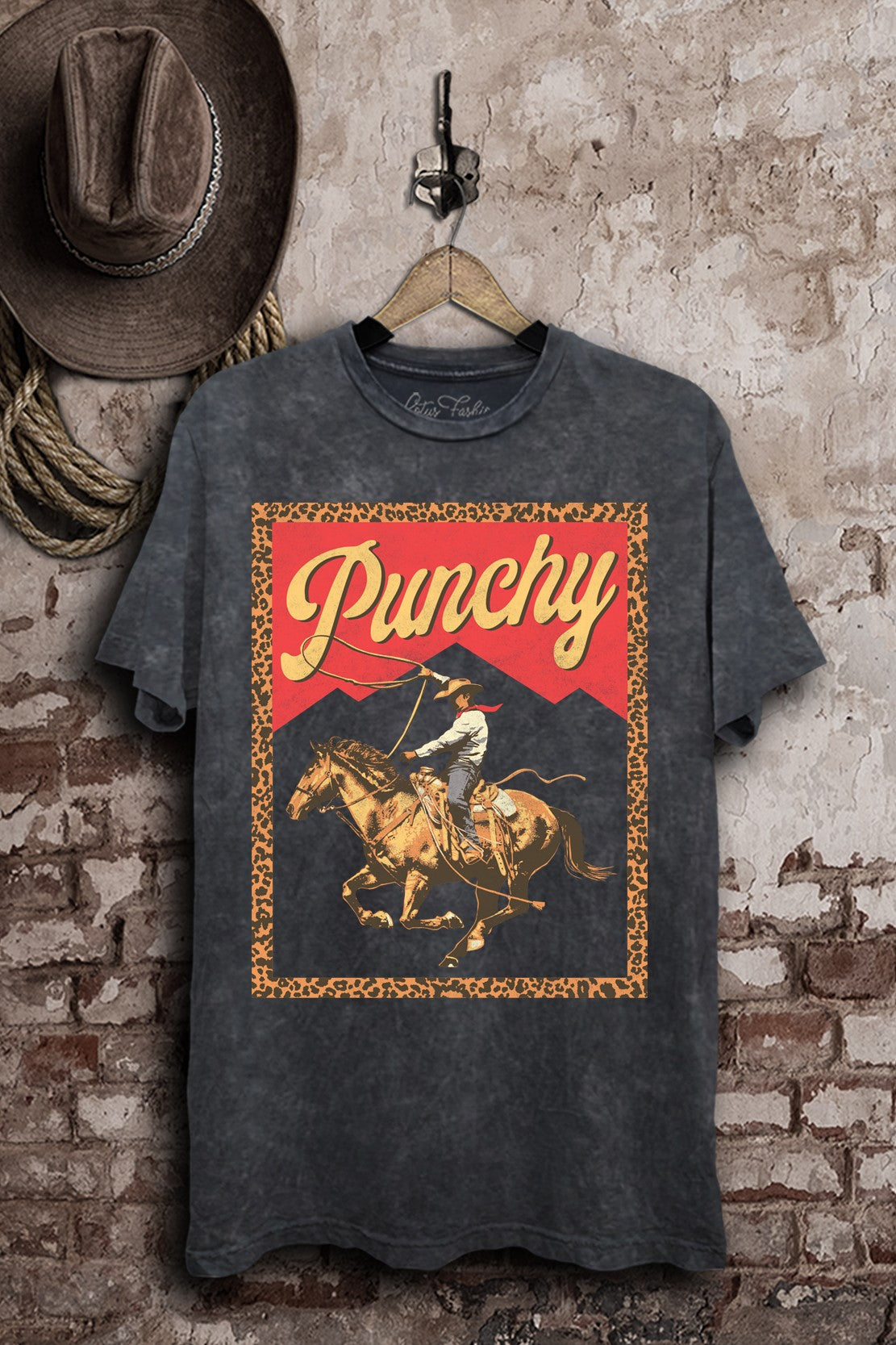 Vintage black mineral-wash boyfriend tee with a roping cowgirl on horseback, red mountain accents, and a leopard-print border.