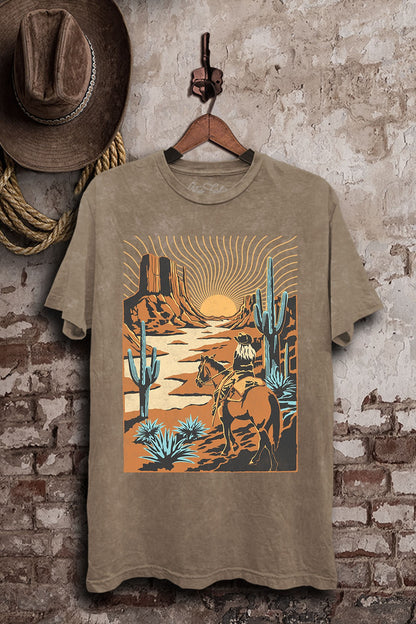 Mocha mineral-washed boyfriend tee featuring a cowboy riding through a sunset desert with mesas, tall cacti, and turquoise-colored plants.