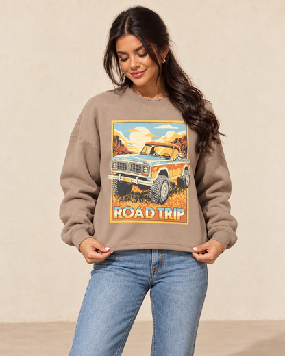 Mocha French terry crewneck sweatshirt featuring a vintage blue and orange off-road truck traveling through a sunlit canyon with Road Trip lettering.