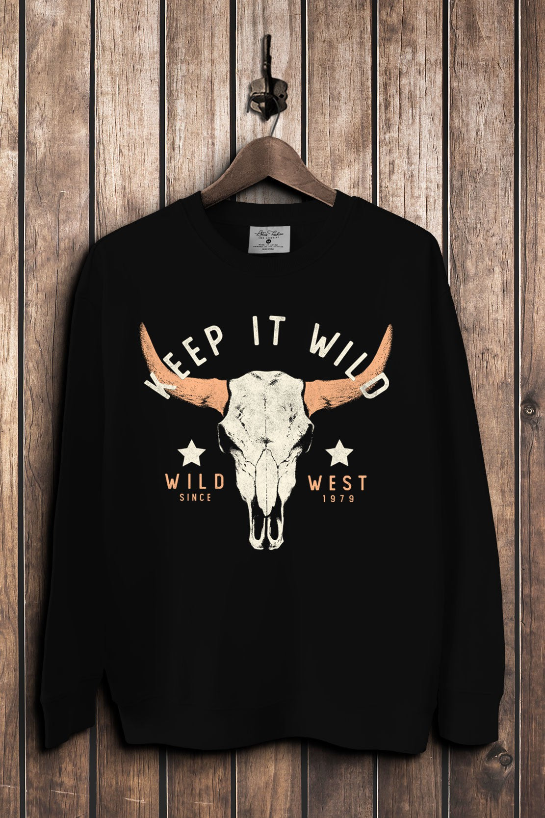 Black French terry crewneck sweatshirt featuring a distressed cow skull with rust-colored horns, stars, and Keep It Wild lettering.