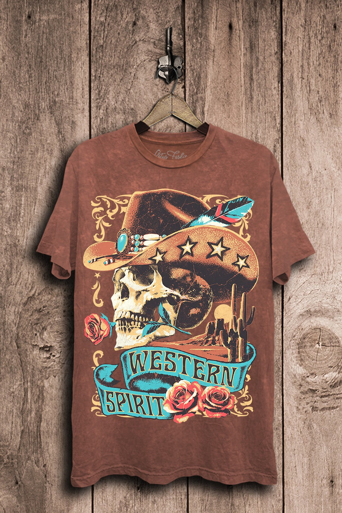 Vintage wine mineral-wash boyfriend tee featuring a cowboy skull in a star-trimmed hat with turquoise accents, roses, feathers, and desert artwork.
